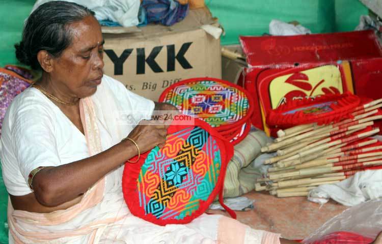 মেলায় বসেই হাত পাখা বানাচ্ছেন এই কারিগর। ছবি : বিপ্লব দিক্ষিৎ।