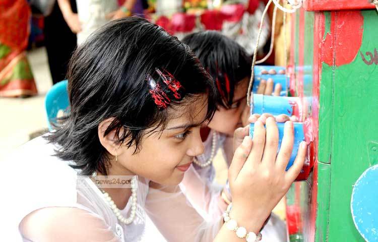 বায়োস্কোপ দেখে আনন্দে হাসছে শিশুটি। ছবি : বিপ্লব দিক্ষিৎ।