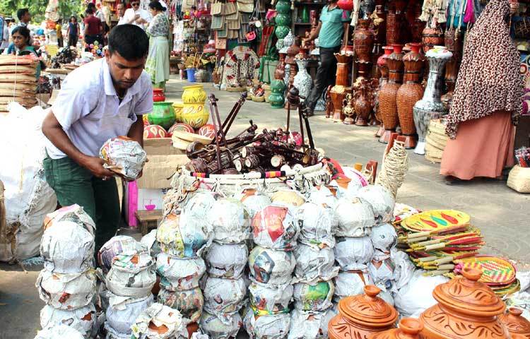 মাটির তৈরি জিনিসপত্র দিয়ে দোকান সাজাতে ব্যস্ত এই ব্যবসায়ী। ছবি : বিপ্লব দিক্ষিৎ।