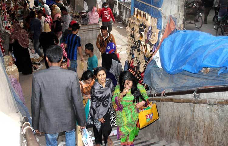 নিউমার্কেট এলাকায় ফুটওভার ব্রিজে ওঠার সিঁড়ির মুখে জুতার দোকানে ক্রেতাদের ভিড় লেগেই থাকে। ফলে ফুটওভার ব্রিজ ব্যবহারকারীদের অনেক কষ্টে পার হতে হয়। প্রশাসন যেনো দেখেও দেখছে না। ছবি : বিপ্লব দিক্ষিৎ