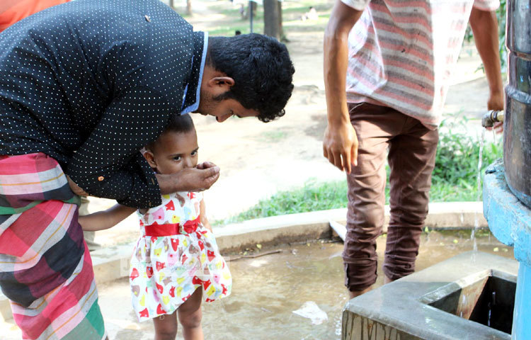 গরমে পিপাসায় কাতর এ শিশুটিকে পানি পান করানো হচ্ছে। ছবি : বিপ্লব দিক্ষিৎ।