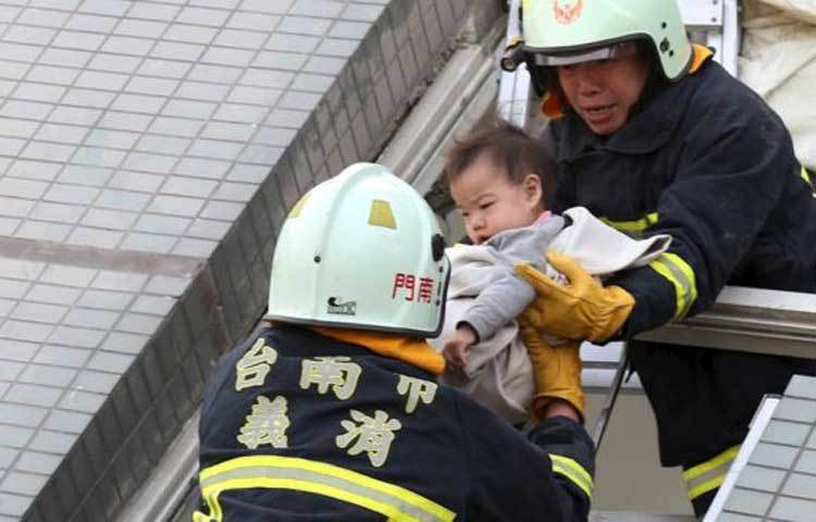 আক্রান্ত ভবন থেকে একটি শিশুকে উদ্ধার করছেন উদ্ধার কর্মীরা। ছবি : বিবিসি
