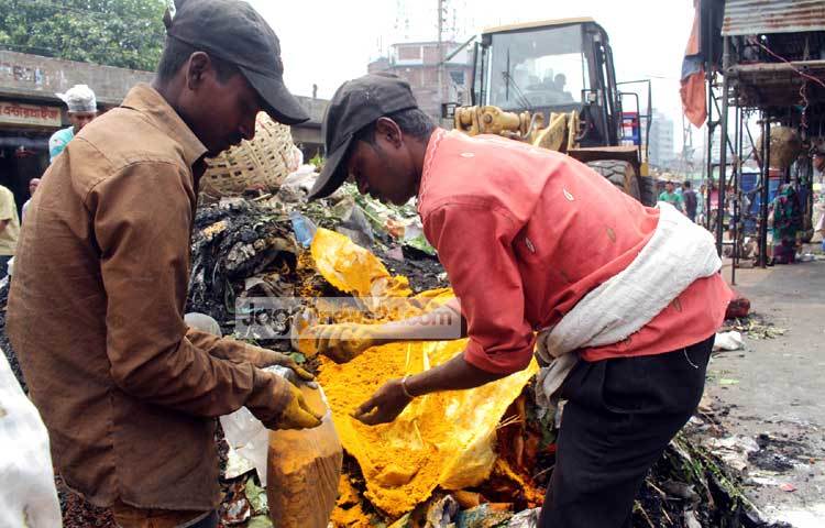 ছিন্নমূল মানুষরা অগ্নিকাণ্ডে ক্ষতিগ্রস্থ মশলার দোকান থেকে হলুদ মরিচের গুঁড়া সংগ্রহ করছে। ছবি : বিপ্লব দিক্ষিৎ।