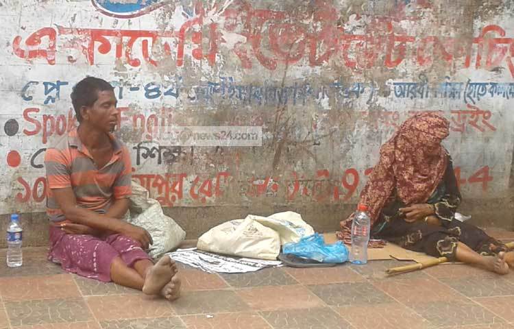 ভিক্ষা পাবার আশায় আজিমপুরের কবরস্থানের ফুটপাথে বসে আছেন। ছবি : মনিরুজ্জামান উজ্জ্বল।