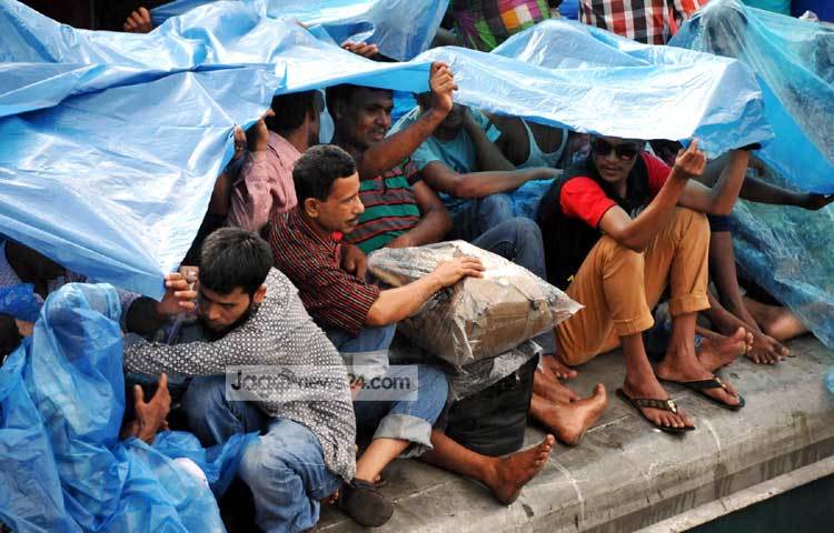 ট্রেনের ছাদের যাত্রীরা বৃষ্টি থেকে বাঁচতে প্রাণান্তকর চেষ্টা চালাচ্ছেন। ছবি : বিপ্লব দিক্ষিৎ।