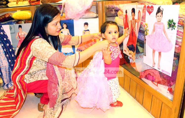 ছোট্ট শিশুটির জন্য তার মা পছন্দের পোশাক কিনতে ব্যস্ত রয়েছেন। তাই শিশুটির গায়ের মাপ নিচ্ছেন। ছবি : বিপ্লব দিক্ষিৎ।