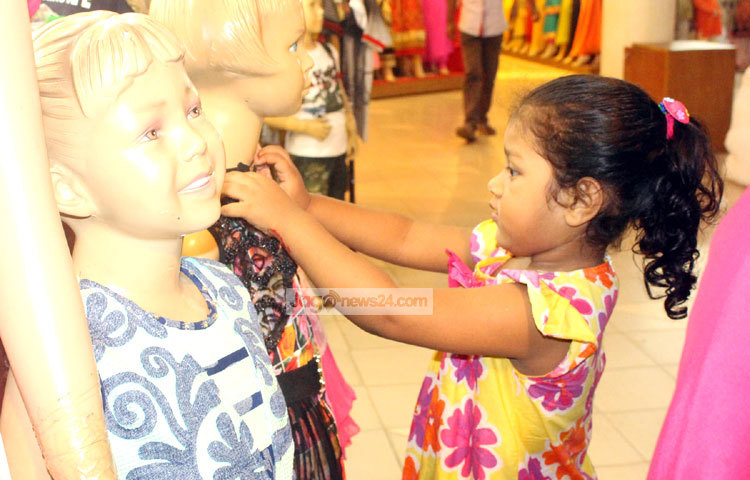 এই শিশুটি ম্যানিকিনের সঙ্গে তার পছন্দের জামাটির মাপ নিচ্ছে। ছবি : বিপ্লব দিক্ষিৎ।