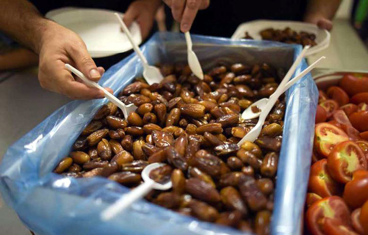 জার্মানির বার্লিনে শরণার্থীশিবিরে ইফতারে খেজুর নিচ্ছে কয়েকজন।