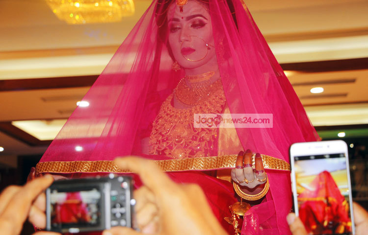 ঢাকা সেনানিবাসের এক কনভেনশন সেন্টারে মাহির বিবাহোত্তর সংবর্ধনা অনুষ্ঠানে তার ঘোমটা পরা ছবি সবাই মোবাইল ফোনের ক্যামেরায় ধারণ করছে। ছবি : জুয়েল।
