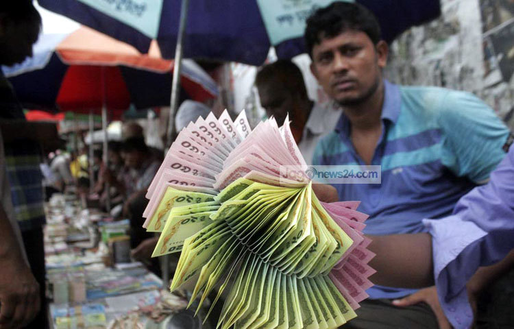 ফুলের মত টাকা সাজানো হয়েছে। ক্রেতাদের জন্য বসে আছেন এই টাকা বিক্রেতা। ছবি : বিপ্লব দিক্ষিৎ।