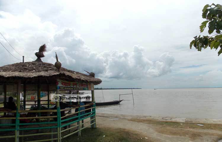 পদ্মার আকাশজুড়ে মেঘের ঘনঘটা। তীরে ছোট এক ঘরে বসেসে মানুষের আড্ডা। ছবি : রবিউল ইসলাম পলাশ।