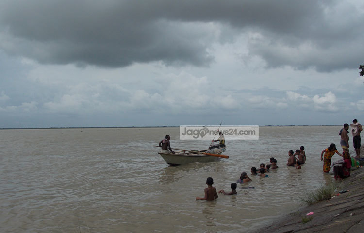 বৃষ্টি ঝরা একটু কমেছে। পদ্মার তীরে বসে গোসল করছেন স্থানীয় বাসিন্দারা। ছবি : রবিউল ইসলাম পলাশ।