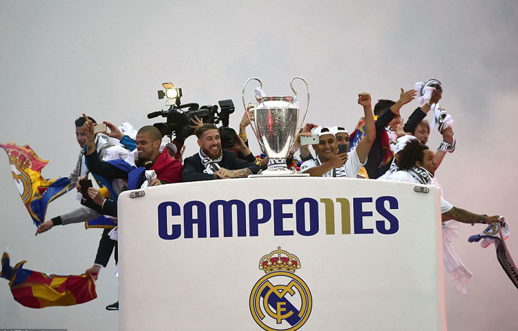 মাঝে চ্যাম্পিয়ন্স লিগ ট্রফি। ছাদ খোলা বাসে ইউরোপজয়ী রিয়াল মাদ্রিদ ফুটবলাররা। মাদ্রিদের রাস্তায়।