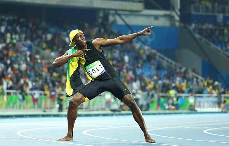 বোল্ট ১০০ মিটার দৌড় জয়ের পর চিরাচেনা ভঙ্গিমায় দাঁড়িয়ে আছেন।