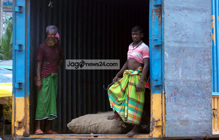 পণ্য পরিবহনের মালামাল তুলছেন দুই শ্রমিক। এভাবে কঠিন পরিশ্রমে তাদের দিন কাটছে। ছবি : রবিউল ইসলাম পলাশ।