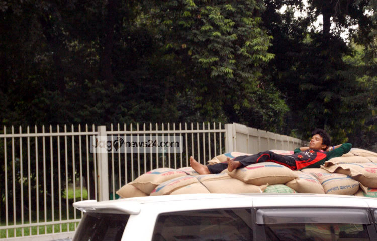 ট্রাকে বোঝাই মালামাল নিয়ে ছুটছে শ্রমিক। ক্লান্তি দূর করতে ট্রাকের বস্তার উপর শুয়ে পড়েছে।ছবি : রবিউল ইসলাম পলাশ।