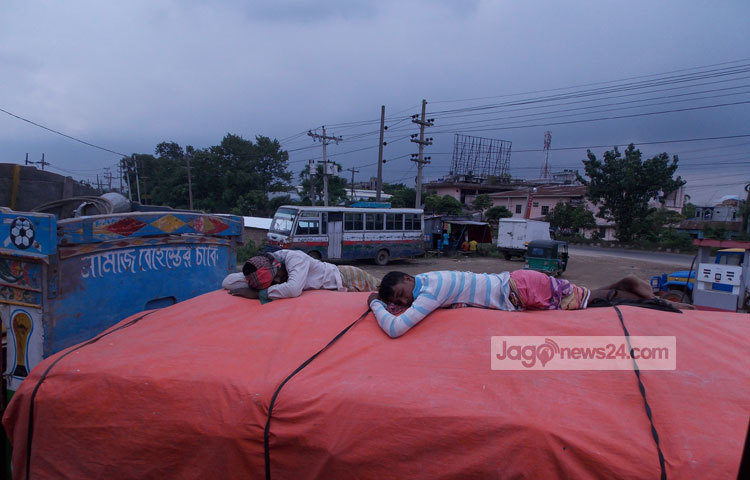 ট্রাকের উপর ঝুঁকিপূর্ণ পরিবেশে শুয়ে আছেন দুই শ্রমিক। চলন্ত ট্রাকের উপর এভাবে শুয়ে থাকলে যে কোন সময়ে ঘটতে পারে দুর্ঘটনা। ছবি : রবিউল ইসলাম পলাশ।