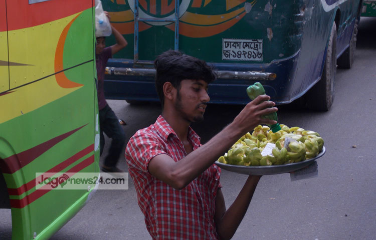 ব্যস্ত সড়কের বাসে বাসে আমড়া বিক্রি করছে এই কিশোর। আমড়া বিক্রি করেই তার জীবীকা নির্বাহ করতে হয়। ছবি : রবিউল ইসলাম পলাশ।