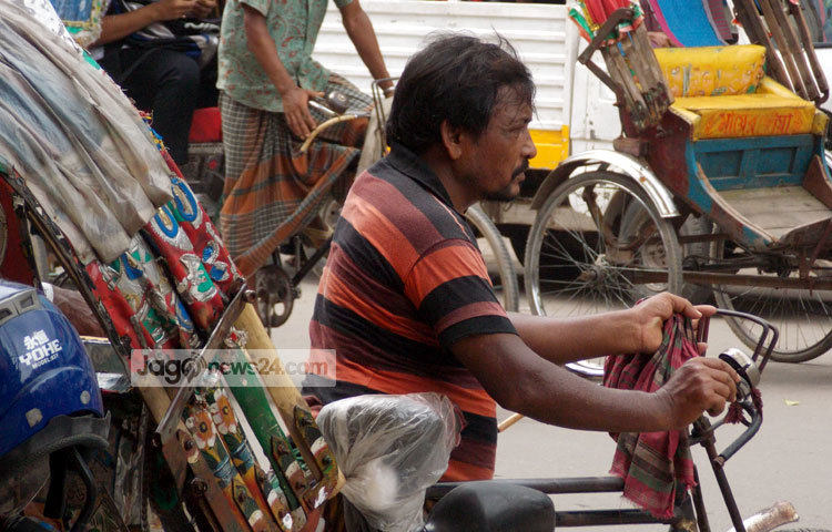 প্রচণ্ড গরমের মধ্যে রিকশা চালাতে চালাতে ক্লান্ত এ রিক্সাওয়ালা। গরমের মধ্যে ঘামে ভিজে একাকার হয়ে গেছেন তিনি। ছবি : রবিউল ইসলাম পলাশ।