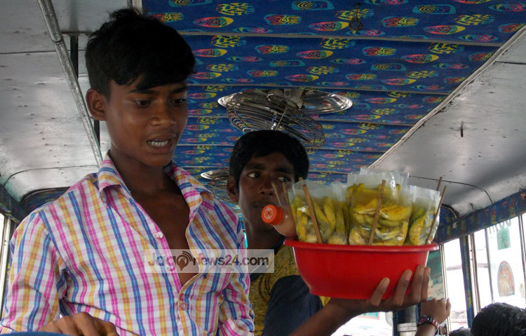 বাসের মধ্যে আমড়া বিক্রি করছে এই কিশোর। অথচ এ বয়সে তার স্কুলে লেখা-পড়া নিয়ে ব্যস্ত থাকার কথা। ছবি : রবিউল ইসলাম পলাশ।