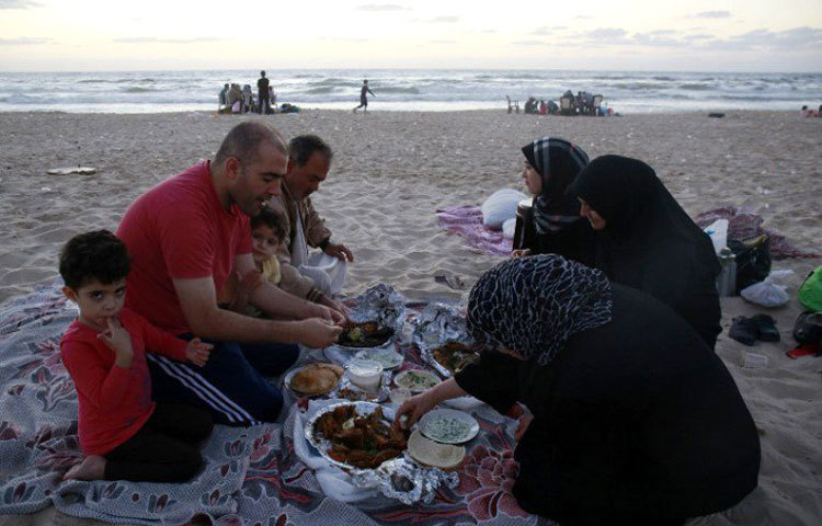 সমুদ্রের ধারে বসে ইফতার করছে প্যালেস্তিনীয় একটি পরিবার।