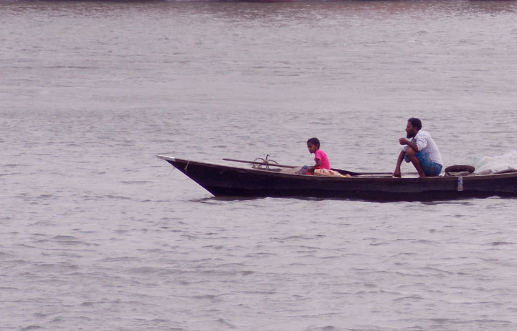 জীবন জীবীকার তাগিদে ছোট্ট শিশুকে নিয়ে উত্তাল পদ্মার বুকে মাছ ধরতে এসেছেন এই জেলে। ছবি : রবিউল ইসলাম পলাশ