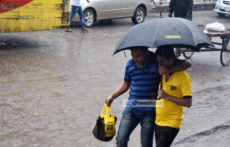 একজনের ছাতায় দুই জন বৃষ্টির হাত থেকে রক্ষা পেতে চাইছে। ছবি : মাহবুব আলম