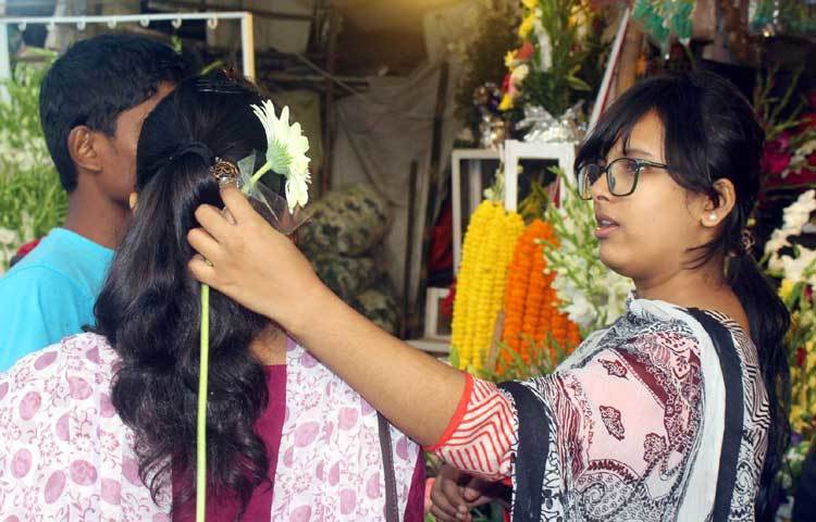 মনের মত ফুল কিনতে ব্যস্ত এই তরুণী। তাই প্রতিটি দোকান ঘুরে ঘুরে তিনি ফুল কিনছেন। ছবি : বিপ্লব দিক্ষৎ