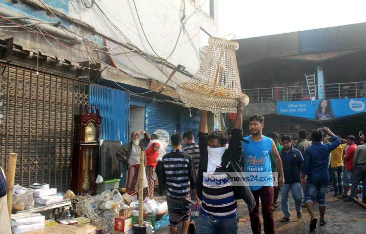 চোখের সামনে পুড়েছে কোটি টাকার সম্পদ। কিছু সম্পদ বাঁচাকে চেষ্টা চালাচ্ছেন দোকানিরা। ছবি : বিপ্লব দিক্ষিৎ