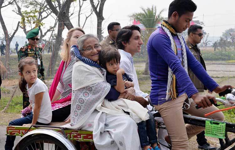 ভ্যানে হাস্যোজ্জ্বল প্রধানমন্ত্রী শেখ হাসিনা। তার কোলে এক নাতি। পাশে আরেক নাতনি। রয়েছেন ভাগ্নে (ছোট বোন শেখ রেহানার ছেলে) রেদওয়ান মুজিব সিদ্দিক ববি ও তার স্ত্রী পেপি।