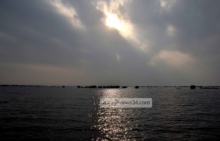 দিগন্ত ছুঁয়েছে হাওরের আকাশ। মেঘের বুক চিড়ে সূর্য উঁকি দিচ্ছে। মেঘের ছায়ায় কালো দেখাচ্ছে হাওরের জল। ছবি : মাহবুব আলম