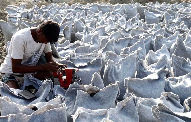 নদী শাসনের বালি ভর্তি বস্তা প্রস্তুত করা হচ্ছে। ইতোমধ্যে পদ্মার দুই পাড়ের সংযোগ সড়কসহ প্রকল্পের নির্মাণ কাজ প্রায় ১৭ শতাংশ শেষ হয়েছে। ছবি : মাহবুব আলম