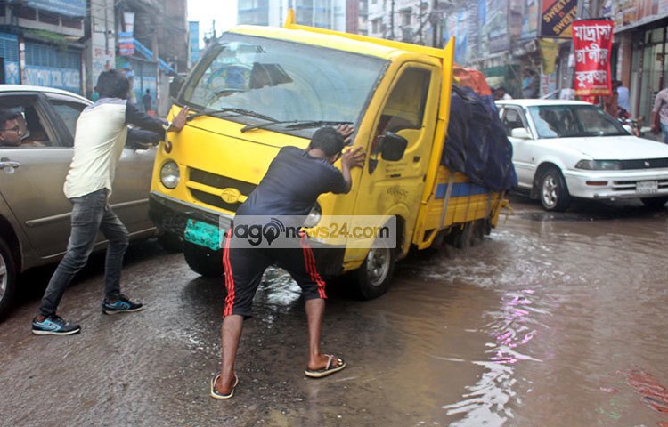 ভাঙা রাস্তায় আটকে পড়েছে গাড়ি। দুইজন মিলে গাড়ি সামনের দিকে নিয়ে যাওয়ার চেষ্টা করছেন। ছবি : বিপ্লব দিক্ষিৎ