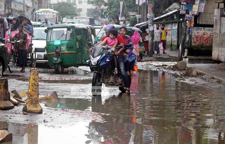 খানাখন্দে ভরা রাস্তা দিয়ে পরিবারের অন্যান্য সদস্যদের সঙ্গে করে ঝুঁকি নিয়ে গন্তব্যে যাচ্ছেন এই মটর সাইকেল আরোহী। ছবি : বিপ্লব দিক্ষিৎ