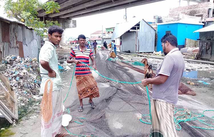 পুরনো জালে দড়ি লাগাচ্ছেন দুই জেলে। ছবি : কাজী সাঈদ