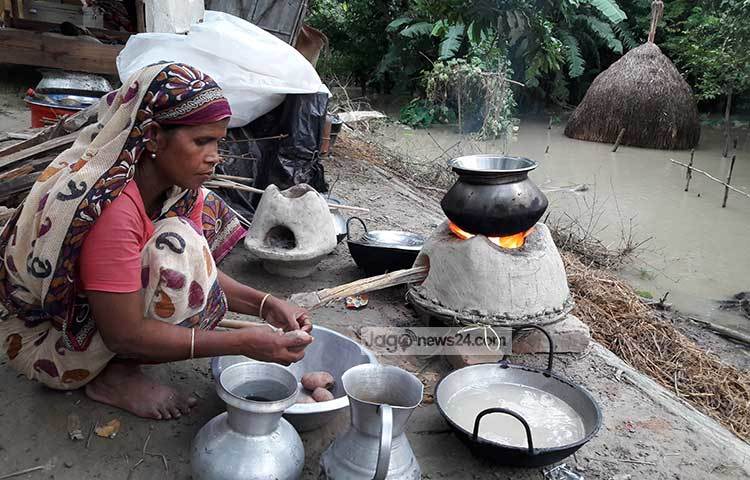 কুড়িগ্রামের একটি গ্রামের দৃশ্য। বন্যায় বাড়ি-ঘর ডুবে যাওয়ায় এই নারী খোলা আকাশের নিচে রান্না করছেন। ছবি : রওশন আলম পাপুল