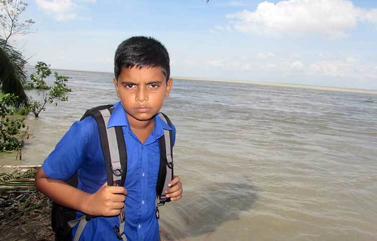 স্কুলে পানি উঠে যাওয়ায় ক্লাস বন্ধ, তাই এই ছাত্রটি বাড়ি ফিরে যাচ্ছে। বন্যার কারণে স্কুল বন্ধ হয়ে যাওয়ায় তার মন ভীষণ খারাপ। ছবি : মো. ছগির হোসেন