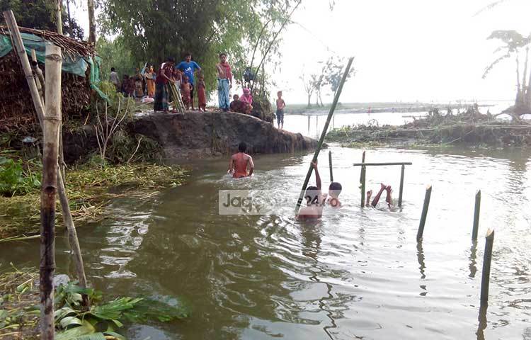 বন্যার পানির প্রবল স্রোতে অনেক জায়গার রাস্তা-ঘাট এভাবে ভেঙ্গে নদীর মত হয়ে গেছে। ভাঙ্গা রাস্তার স্থানে সাঁকো নির্মাণ করছেন এলাকাবাসী। ছবি : রবিউল হাসান