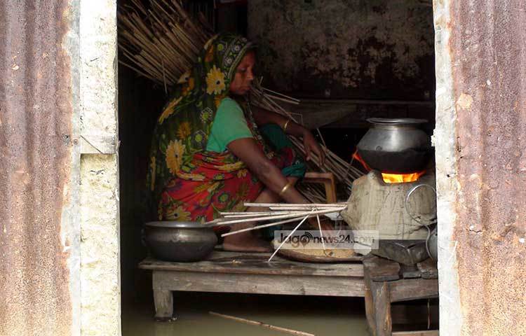 জামালপুরের সার্বিক বন্যা পরিস্থিতির ভায়াবহ অবনতি ঘটেছে। ইসলামপুরের চিনাডুলি ইউনিয়নের বলিদাহ গ্রামে বন্যা কবলিত একটি বাড়িতে চৌকির উপর বসে রান্না করছেন এক গৃহিনী। ছবি : শুভ্র মেহেদী