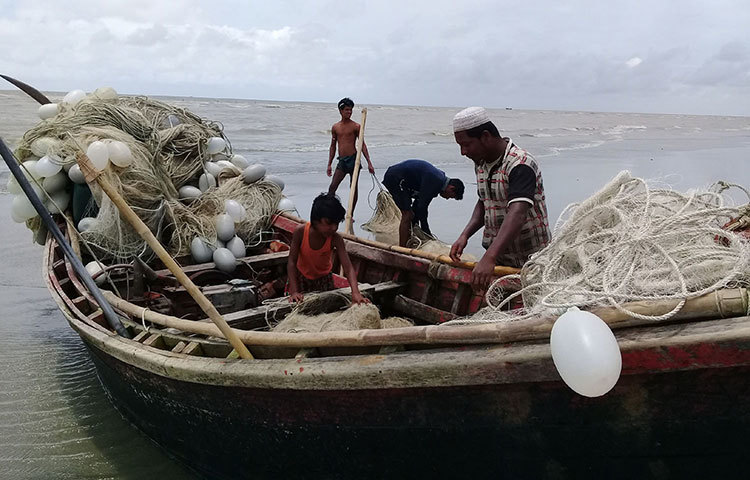 সাগর থেকে তুলে আনা জাল নৌকা ট্রলার থেকে নামাতে জেলেদের সাহায্য করেছে জেলে কন্যা মারুফা। ছবি : কাজী সাঈদ