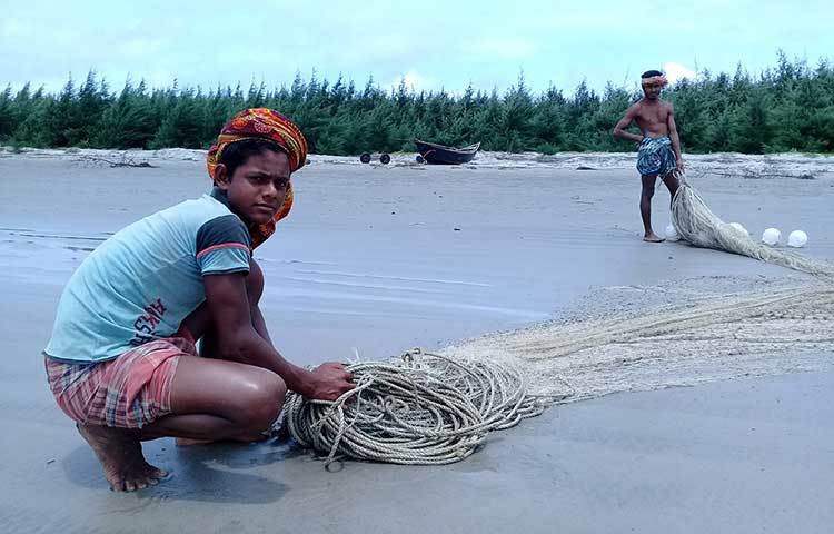 ইলিশ না পেয়ে সমুদ্রে থেকে তুলে আনা জাল গুছিয়ে আটি বাঁধছেন দুই কিশোর জেলে। ঋণের বোঝা মাথায় নিয়ে চরম বেকায়দায় তারা। ছবি : কাজী সাঈদ