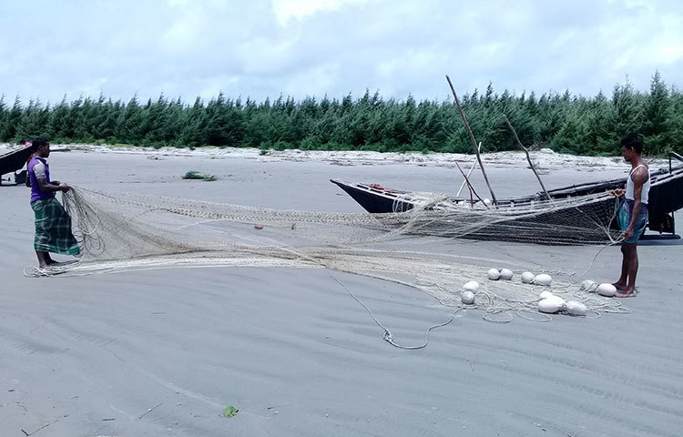 সমুদ্র থেকে তুলে আনা এলোমেলো জাল গোচাচ্ছেন দুই জেলে। ছবি : কাজী সাঈদ