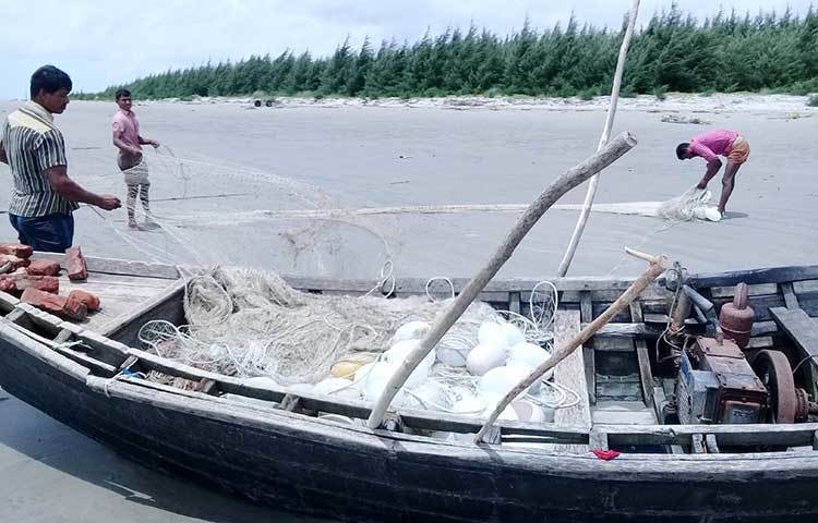 নৌকা ট্রলার থেকে জাল নামাচ্ছেন হতাশাগ্রস্ত তিন জেলে। ছবি : কাজী সাঈদ