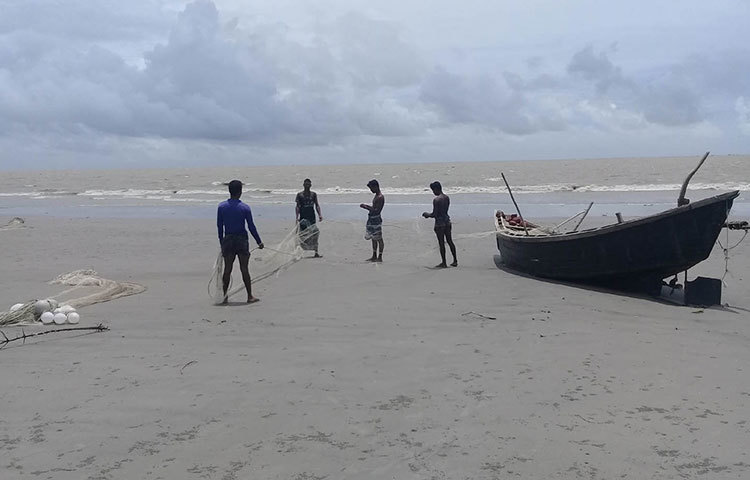 সমুদ্র থেকে তুলে আনা এলোমেলো জাল গোছাচ্ছেন চার জেলে। ছবি : কাজী সাঈদ