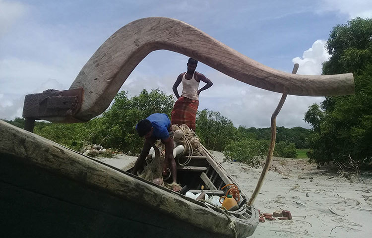 জাল ভর্তি নৌকা ট্রলার নিরাপদ স্থানে রেখে জাল গুছিয়ে নেয়ার কাজে ব্যস্ত দুই জেলে। ছবি : কাজী সাঈদ