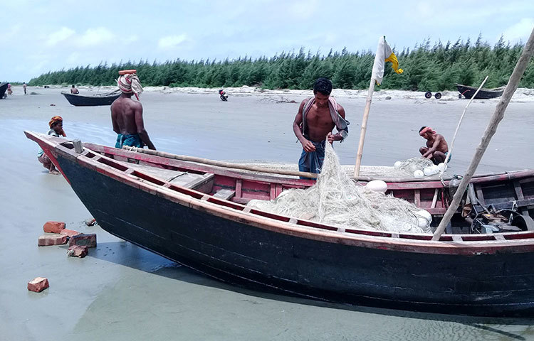 চোখে-মুখে হতাশার ছাপ নিয়ে সাগর থেকে তুলে আনা জাল গোছাচ্ছেন চার জেলে। ১৫ পিস জালে মাত্র তিনটি ইলিশ পেয়েছেন। ছবি : কাজী সাঈদ