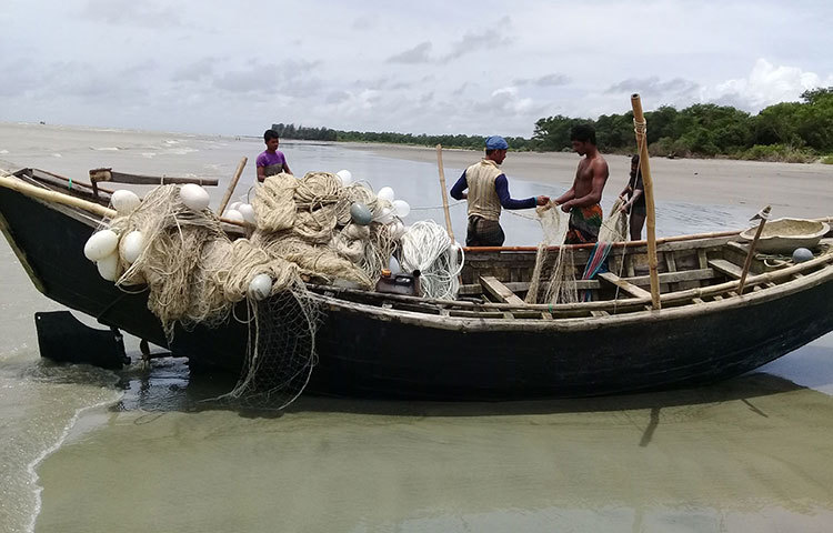 সমুদ্র থেকে তুলে আনা এলোমেলো জাল গোচানোর কাজে ব্যস্ত চার জেলে। ছবি : কাজী সাঈদ