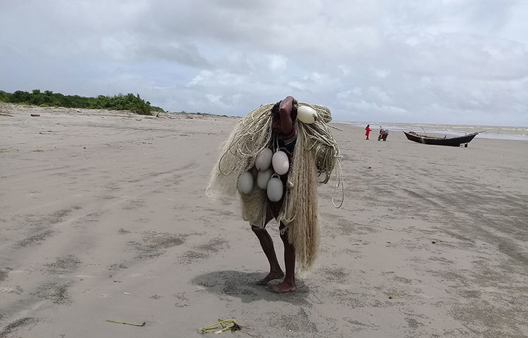 সমুদ্র থেকে তুলে আনা জাল জেলেপাড়ায় নিয়ে যাচ্ছেন এক জেলে। ছবি : কাজী সাঈদ