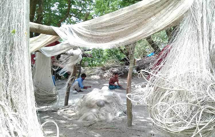 উত্তাল সাগরে ছেড়া জাল বুনানোর কাজে ব্যস্ত দুই জেলে। ছবি : কাজী সাঈদ