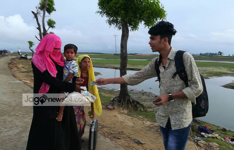 রোহিঙ্গা নারীর হাতে নগদ টাকা ও শুকনা খাবার তুলে দিচ্ছেন এক শিক্ষার্থী। ছবি : মাহবুব আলম